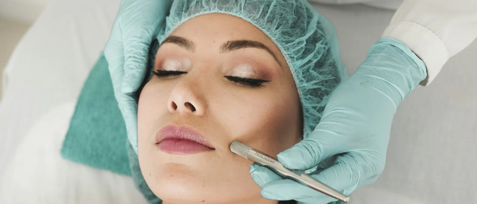 A skin specialist wearing gloves performs a facial treatment in a clean, clinical setting.